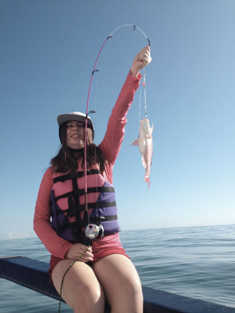 Alyx holding a fish on a fishing pole.