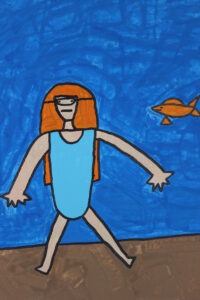 Girl with a snorkel on in the water with a orange fish.